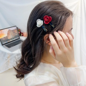 Set of 2 acetate camellia flower hair clips in red and white on a model side view