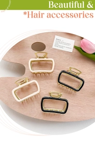 Detail of elegant rectangular metal hair claws in black and cream on a wooden base