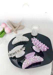 Detail of four acetate hair claws with pearl flower patterns and rhinestones on black tray