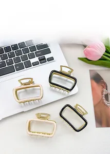Detail of square alloy hair claws in black and cream with gold trim on desk