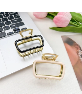 Detail view of gold alloy hair claws with black and beige enamel on a laptop