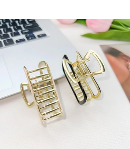 Detail of two-piece golden alloy square claw clips with black and pink enamel finish