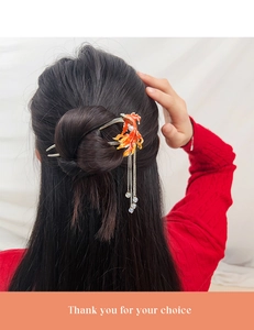 Detail of koi fish hair stick with red tassels and pearl on model hair bun