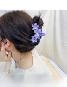 Détail montrant une pince à cheveux fleurie mate violette portée sur le côté des cheveux