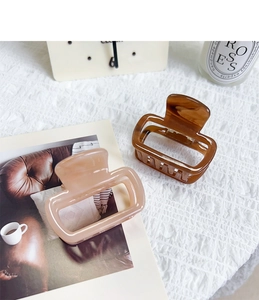 Détail de grandes pinces à cheveux rectangulaires en acétate beige et ambre