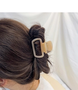 Détail de la pince à cheveux carrée en acétate beige sur modèle avec coiffure ondulée