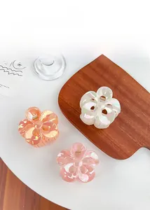 Detailed display of colorful plumeria flower hair claws in pearl white, orange, and pink