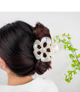 Iridescent white flower hair claw clip shown holding a hair bun on a female model