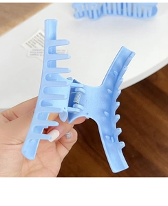 Close-up of a matte light blue shark hair claw clip with a strong metal spring and cross teeth