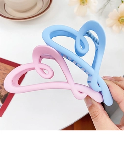 Macro detail of large matte candy-colored heart-shaped hair claws in pink and blue