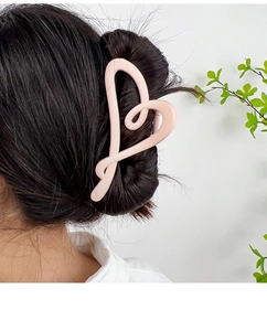 Pink heart-shaped matte hair claw clip shown in a stylish updo on a female model