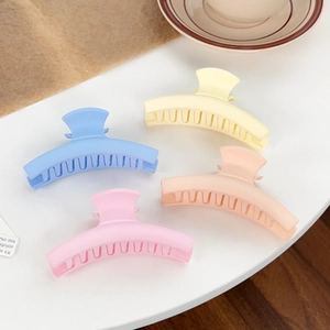 Set of four matte macaron plastic hair claws for women in candy colors on a desk