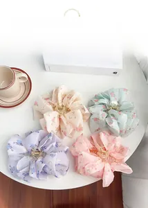 Floral fabric bow hair claws in pastel colors with embroidery detail on white table