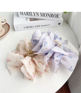 Detail of floral chiffon fabric hair claws in beige and lavender on a white table