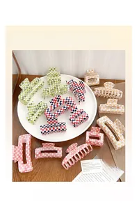 Détail de pinces à cheveux à damier colorées de diverses formes sur une assiette blanche