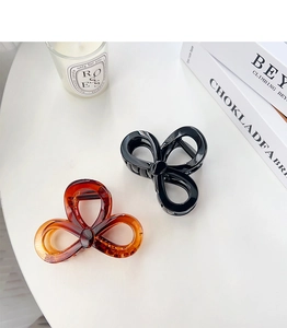Detail of elegant butterfly claw clips in black and amber with high-gloss finish