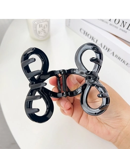 Detailed view of a large black bow hair claw clip with a strong metal spring mechanism