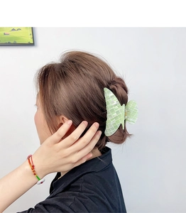 Détail d'une pince à cheveux papillon vert clair avec texture coquillage sur modèle
