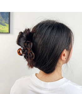 Detail view of a vintage tortoiseshell bow hair claw clip styled on a low bun updo