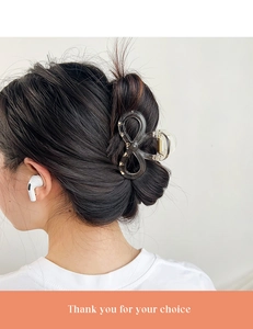 Detail of large translucent grey-black bow-shaped hair claw clip on a woman's updo hairstyle