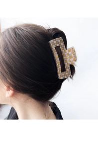 Gros plan sur une grande pince à cheveux rectangulaire à damier doré et argenté brillant