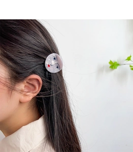 Artistic acetate hair clip featuring minimalist face design and red lips on model