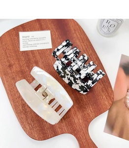 Detail view of large acetate claw clips in marble and tortoiseshell patterns on wood