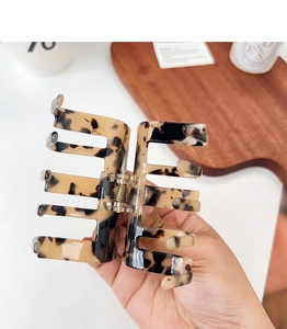 Detail of a large square tortoise shell hair claw clip held by hand for scale