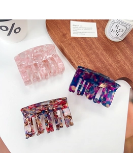Detailed view of large acetate hair claws in pink marble and tortoise shell patterns
