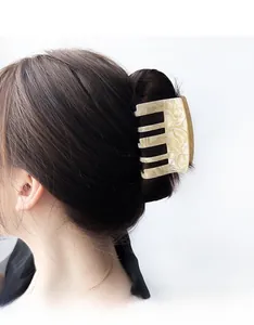 Close-up of a large cream marble acetate claw clip securing a bun on a female model