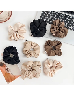 Λήψη flat lay από οκτώ σατέν λαστιχάκια μαλλιών σε γήινους τόνους σε λευκό γραφείο