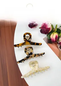 Three large tortoiseshell acetate hair claws in dark, light, and marble cream finishes