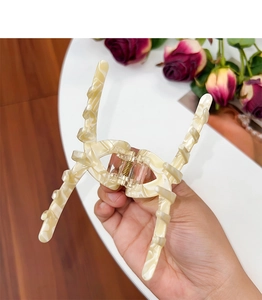 Detail view of a large cream marble acetate hair claw clip with sturdy metal spring