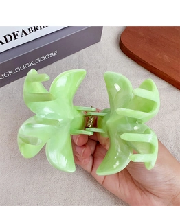 Dettaglio di una grande pinza per capelli verde chiaro con trama marmorea in mano