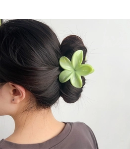 Dettaglio del fermaglio a fiore verde chiaro sui capelli che mostra la finitura opaca e i petali
