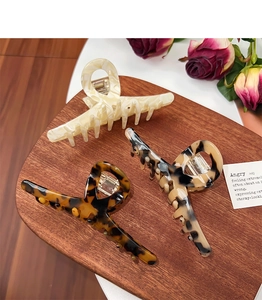 Three large tortoiseshell and marble acetate hair claws on a vintage wooden tray
