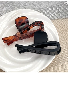 Détail de pinces à cheveux ambre écaille et noir mat avec un design croisé élégant