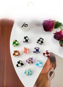 Flat lay of 11 colorful checkerboard mini hair clips in acrylic material on a white table