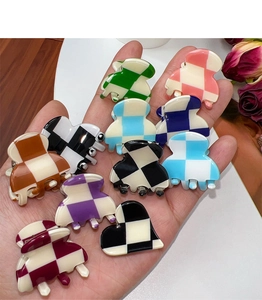 Macro view of mini checkered hair claws in assorted colors held in hand for scale