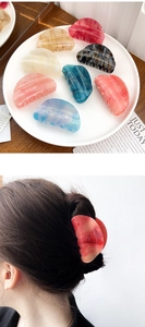 Detail of glitter acrylic hair claws showing marble texture and elegant hair styling