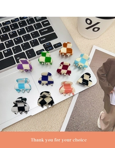 Mini checkered acetate hair claws in various colors placed on a silver laptop