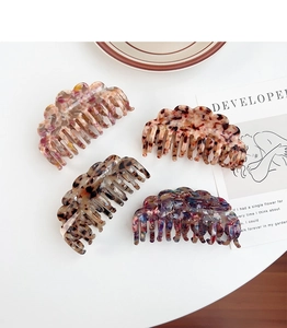 Flat lay of four tortoiseshell acetate hair claws in marble and floral patterns on desk