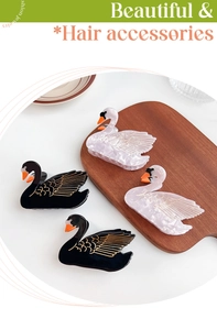 Close-up of elegant swan hair clips in black and white acetate with golden accents