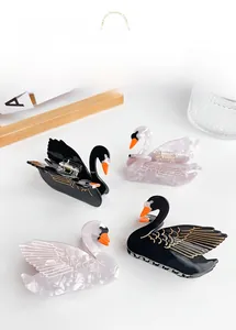 Detail showing elegant black and pearly white swan hair claws with gold wing patterns