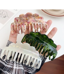 Detailed view of wave-shaped acetate claw clips in marble pink, green, and pearl white