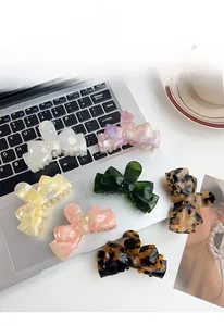 Flat lay of seven colorful acetate bow hair claws on a laptop with a fashion magazine