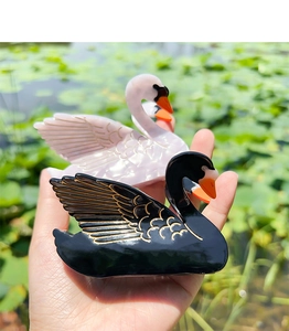 Detailed macro view of swan-shaped acetate hair claws with elegant gold outlines and accents