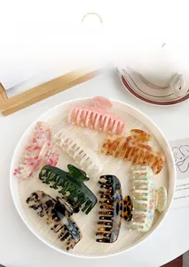 Set of eight acetate hair claws in various marble and floral patterns on a white tray