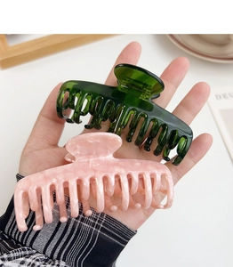 Close-up of large acetate hair claws in dark green and pink marble showing sturdy double teeth