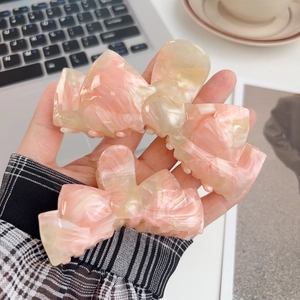 Pink marble acetate bow claw clip and medium hair clamp set shown in office setting